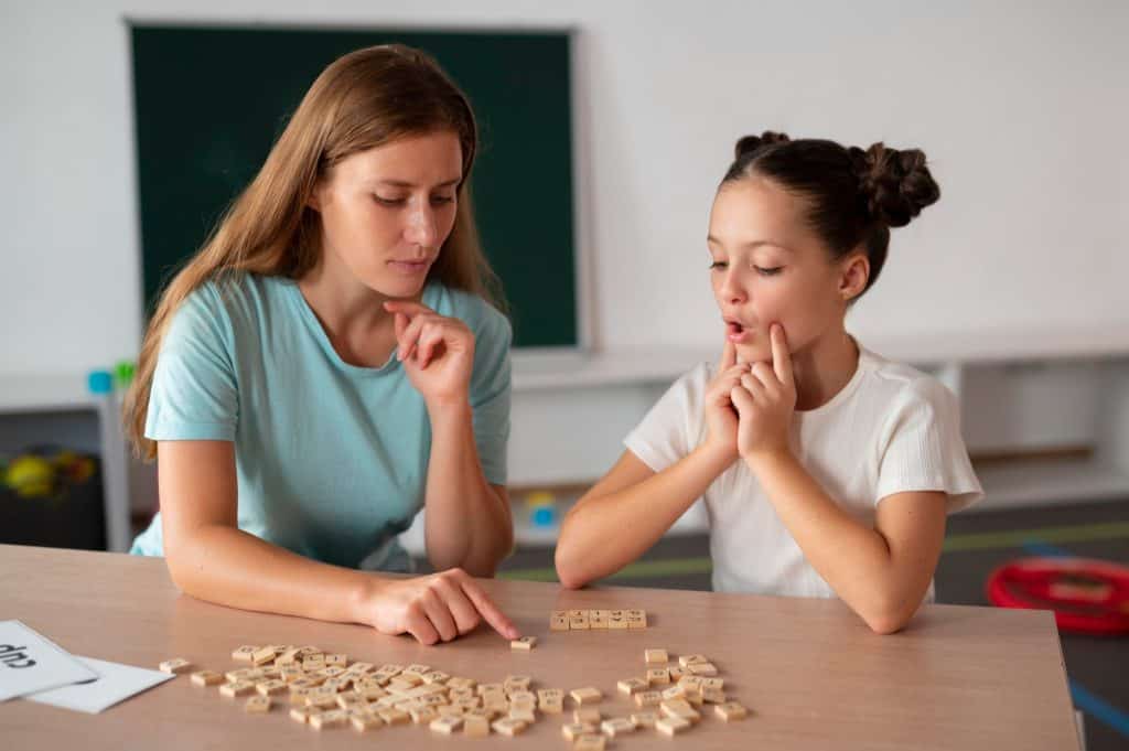 Pathologist helping little girl speech therapy indoors